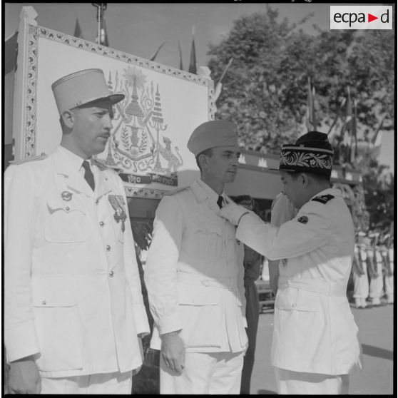 Le roi du Cambodge Norodom Sihanouk décore un militaire français au cours d'une cérémonie commémorant l'anniversaire de la rétrocession de Battambang par le Siam.