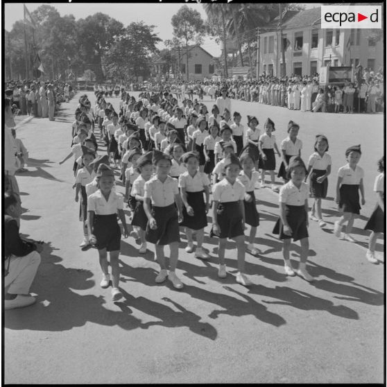 Défilé des écoliers devant la tribune officielle lors d'une cérémonie pour l'anniversaire de la rétrocession Battambang par le Siam.