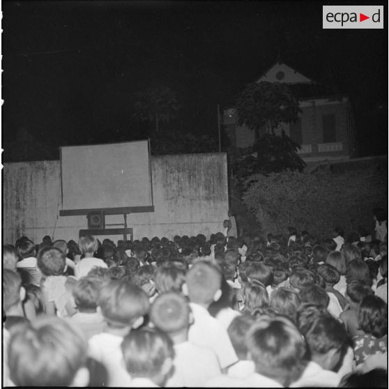 Projection d'un film en plein air le soir sur une place au Cambodge