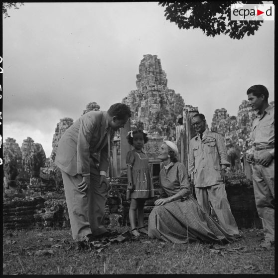 Richard Nixon, vice-président des États-Unis, et son épouse Pat Nixon posent avec une petite fille cambodgienne devant le Bayon.