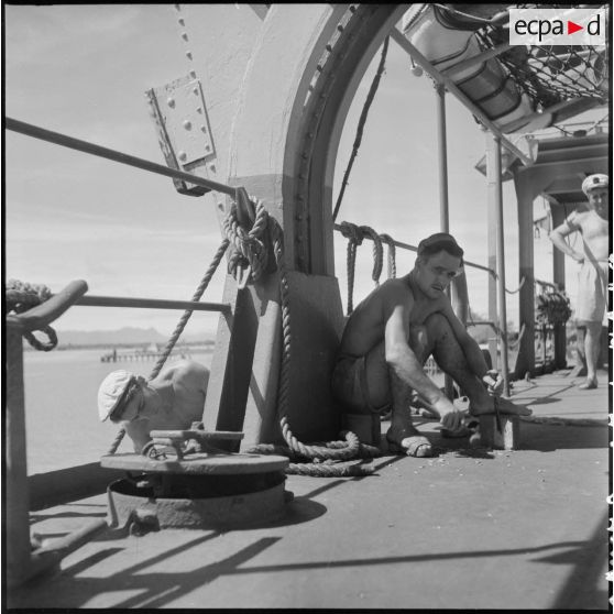 Sur le pont du LST Rance, des marins effectuent des travaux d'entretien.