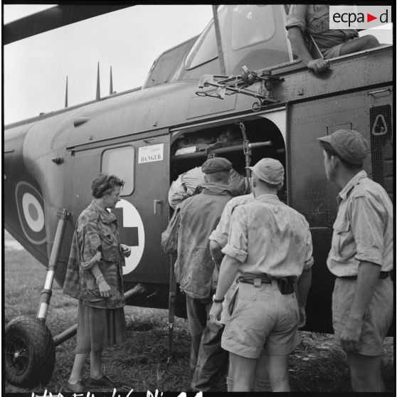 Arrivée des premiers grands blessés de Diên Biên Phu par hélicoptère Sikorsky sur le terrain d'aviation de Luang Prabang, immédiatement pris en charge par le personnel médical.