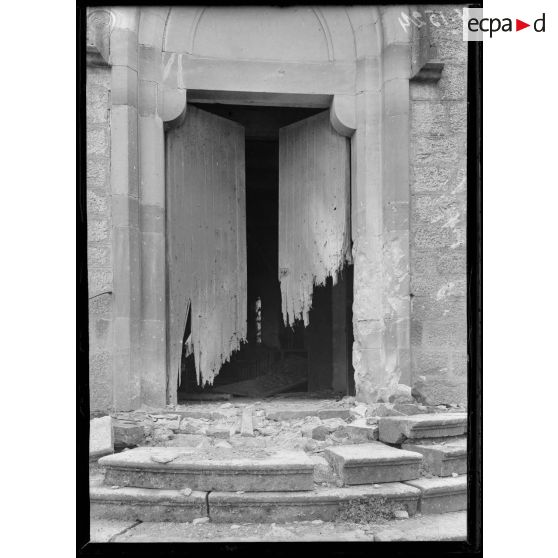 Hénaménil (Meurthe-et-Moselle). Entrée de l'église. Porte déchiquetée par les balles. [légende d'origine]