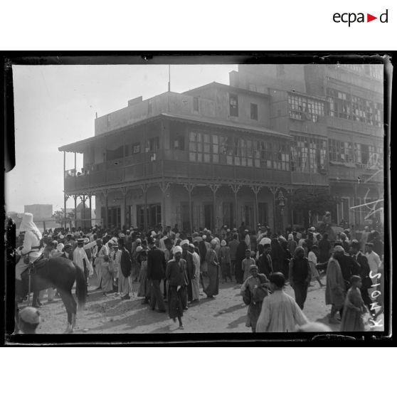 Port-Saïd, 7 h 20. La foule près d'un trou de bombe. A droite, le café près duquel la bombe est tombée (6 morts). [légende d'origine]