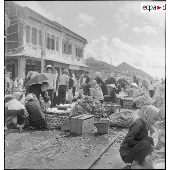 Scène de marché avec des vendeurs ambulants dans les rues de Saigon.