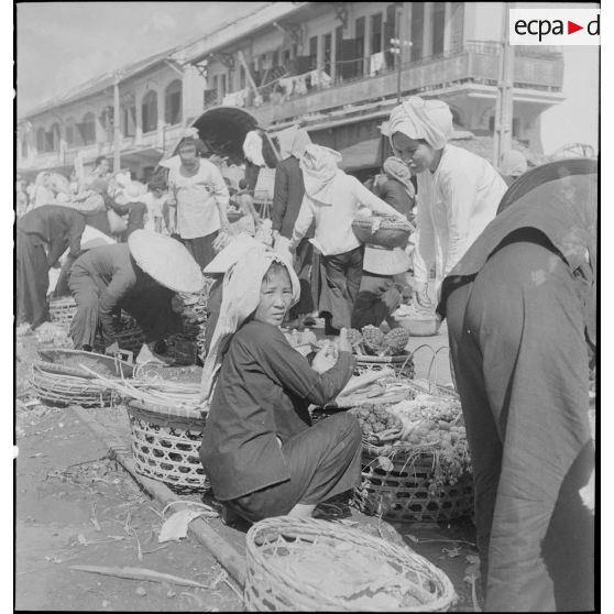 Scène de marché avec des vendeurs ambulants dans les rues de Saigon.