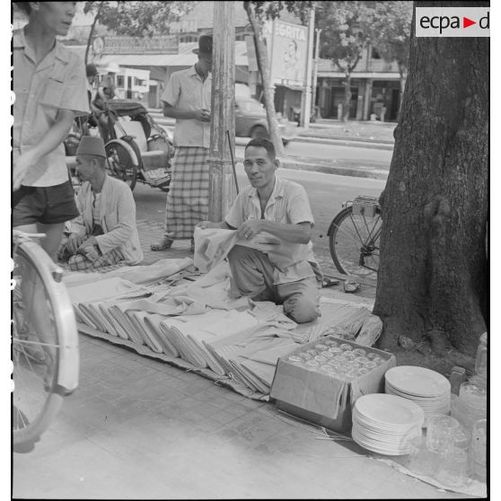 Un marchand de tissus dans les rues de Saigon.