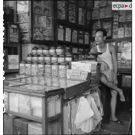 Portrait d'un commerçant dans une échoppe de confiseries à Saigon.