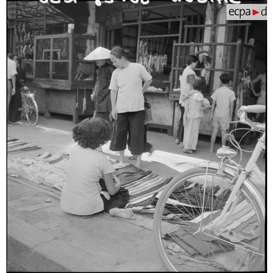 Une vendeuse de vêtements installée à même le sol dans une rue commerçante à Saigon.