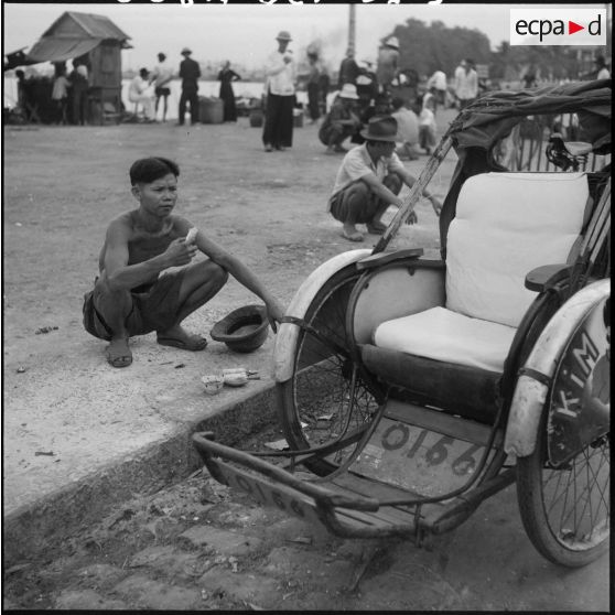 Un conducteur de cyclo-pousse mange sur un trottoir à Saigon.