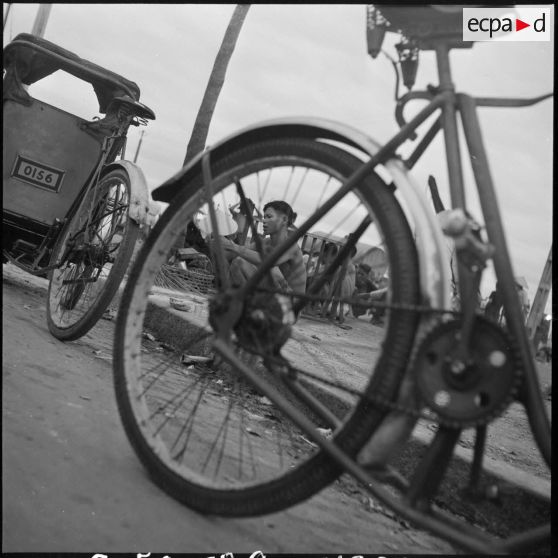 Un conducteur de cyclo-pousse mange sur un trottoir à Saigon.