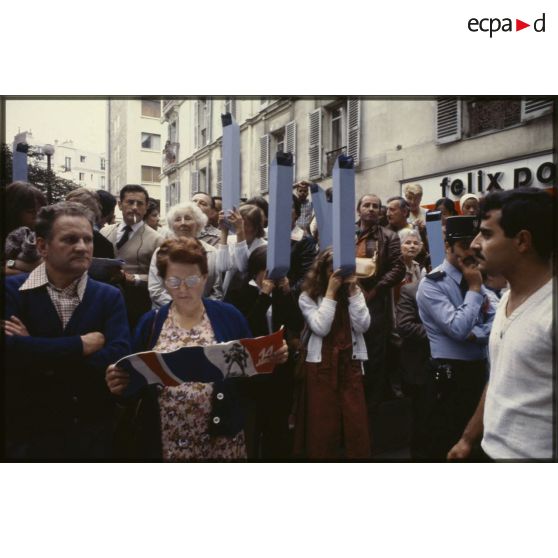 Lors du défilé du 14 juillet 1979 à la Bastille, le public, équipé de périscopes en papier, ou consultant le programme de l'événement.