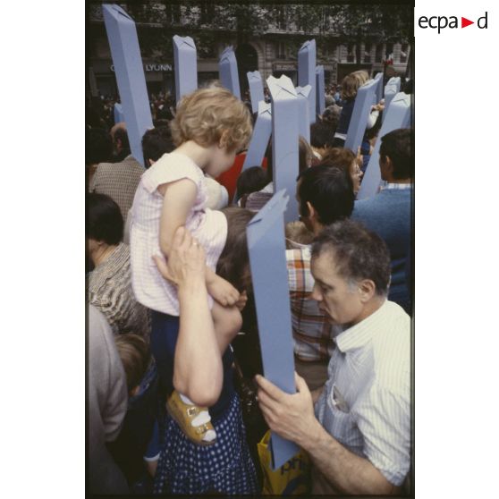 Lors du défilé du 14 juillet 1979 à la Bastille, le public est équipé de périscopes en papier, ou juche les plus jeunes sur les épaules.