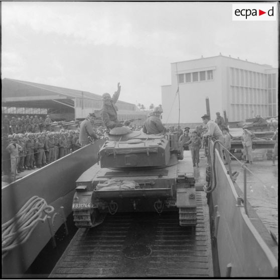 Un char AMX 13 débarque d’une barge. [Description en cours]