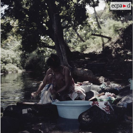 Portrait d'une femme tahitienne à la lessive au bord d'une rivière.