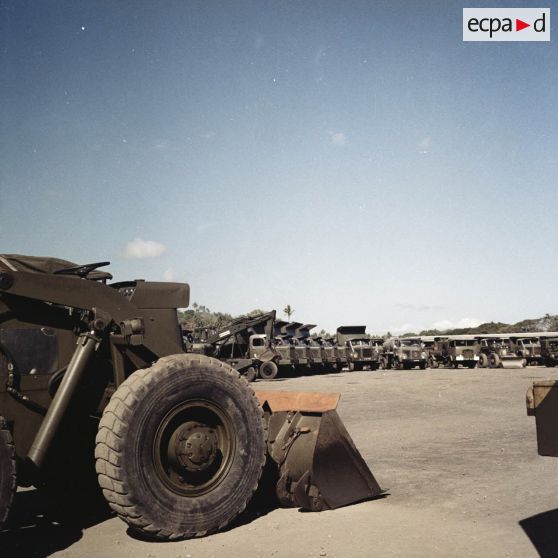 Parc d'engins du génie et de camions à benne dans un camp militaire, peut-être à Arue.