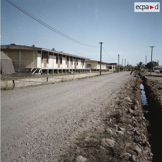 Logements préfabriqués, voirie et canalisation de rivière dans un camp militaire, peut-être à Arue.