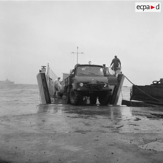 Embarquement d'un camion Unimog et d'une remorque sur une barge du transport de chalands de débarquement (TCD) Ouragan ou un landing craft tank (LCT).