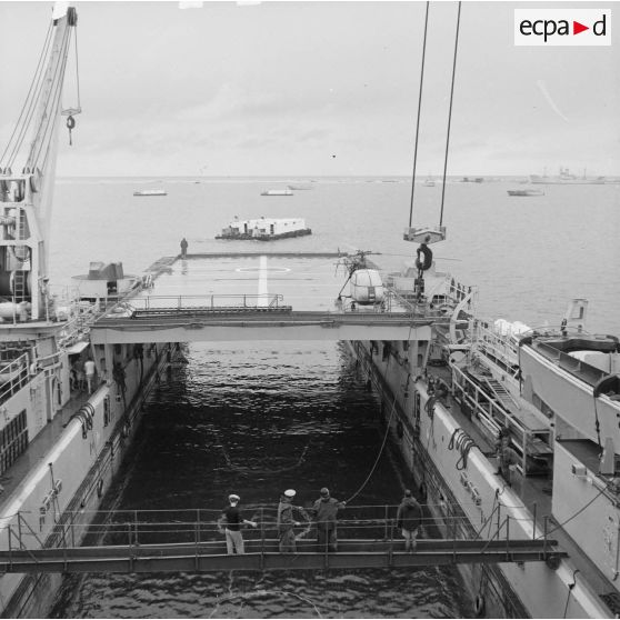 Manoeuvre dans le radier du transport de chalands de débarquement (TCD) Ouragan. En arrière-plan, des landing craft tank (LCT) ou barges de débarquement.