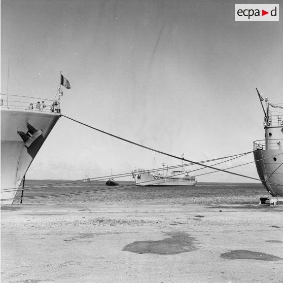 Vue entre deux bâtiments (le Rance (A618) et le Tarn (A771)) à quai au port de Moruroa de l'arrivée du pétrolier caboteur Aber Wrach (A619), ravitailleur en produits blancs, au remorquage.