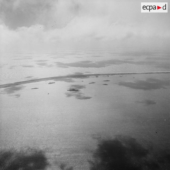 Vue aérienne de l'atoll de Moruroa et de la force Alpha au mouillage dans le lagon.