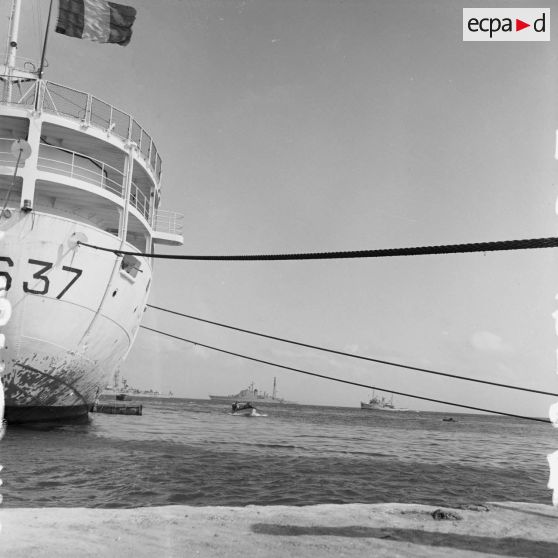 En arrière-plan du bâtiment-base (BB) Maurienne (A637) à quai au port de Moruroa, la force Alpha au mouillage dans le lagon, dont le croiseur De Grasse (C610) et le remorqueur de haute-mer Hippopotame (A660).