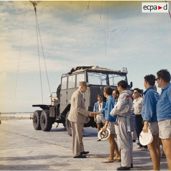 Le général Charles De Gaulle, président de la République, se fait présenter le personnel civil du site de Moruroa. En arrière-plan, un camion Berliet auquel est arrimé le ballon du prochain tir Bételgeuse.