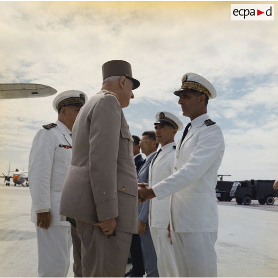 A l'aéroport de Moruroa, le général Charles De Gaulle, président de la République, salue le contre-amiral André Storelli, commandant du groupe aéronaval (GAN) du Pacifique, en présence du vice-amiral Jean Lorain, commandant du groupe opérationnel des expérimentations nucléaires (GOEN).