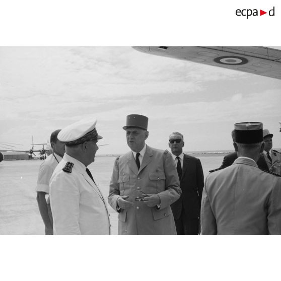 Le général Charles De Gaulle, président de la République, et le vice-amiral Jean Lorain, commandement du groupe opérationnel des expérimentations nucléaires (GOEN), Pierre Messmer, ministre des Armées, au pied de l'avion à l'aéroport de Moruroa.