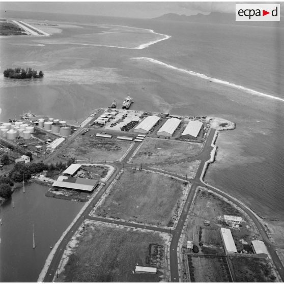 Vue aérienne du site portuaire Fare ute de Papeete en construction, au second plan à gauche Motu uta puis l'aéroport de Faa'a, vers 1963-1964.