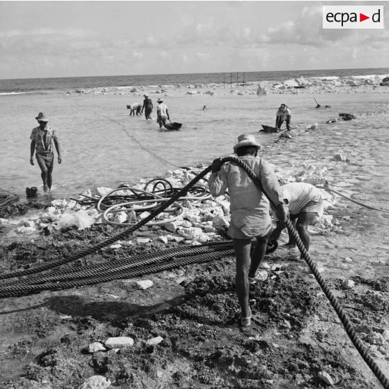 Ouvriers au travail sur le rivage. Construction du site de Moruroa.