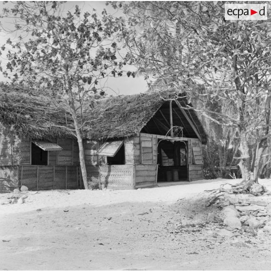 Infrastructures de la zone de vie. Peut-être sur l'atoll d'Hao. Le Tahiti bar (enseigne de néon).