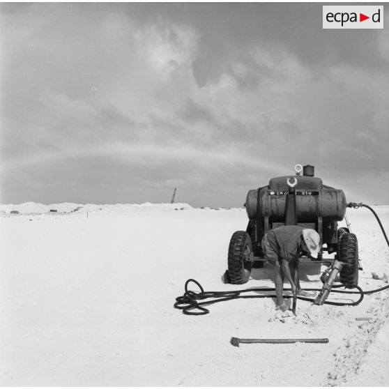 Remorque compresseur pour marteau-piqueur et ouvrier sur un chantier de construction de piste. Peut-être sur l'atoll de Moruroa.