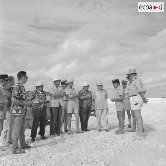 Hommes politiques polynésiens (Jacques Tauraa, président de l'Assemblée territoriale, Alfred Poroï, maire de Papeete, Jean Roy Bambridge, conseiller municipal de Papeete) écoutant l'exposé d'un militaire lors d'une visite à Moruroa sur le site du centre d'expérimentation du Pacifique (CEP) en construction, vers fin février-fin avril 1964.