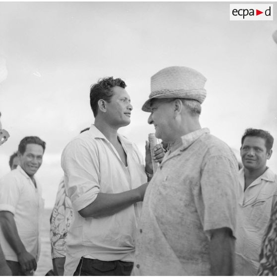 Alfred Poroï, maire de Papeete, au milieu d'ouvriers polynésiens lors d'une visite à Moruroa sur le site du centre d'expérimentation du Pacifique (CEP) en construction, vers fin février-fin avril 1964.