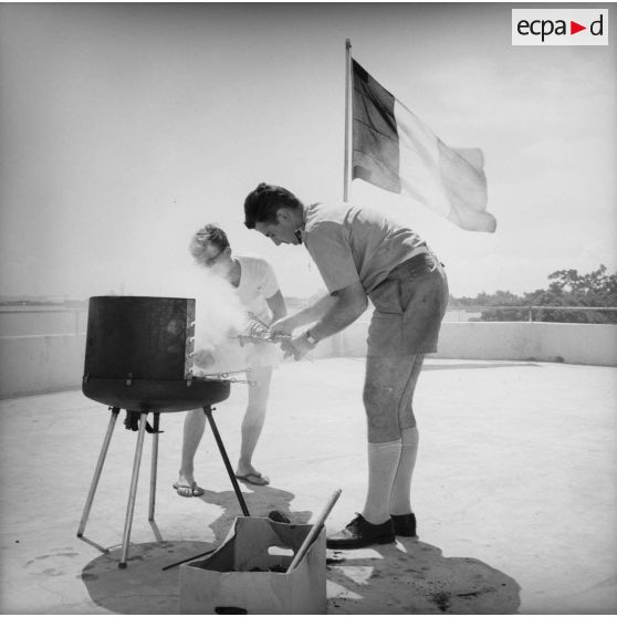 Préparation d'un barbecue et drapeau français lors de la fête de Camerone de la Légion étrangère, 30 avril 1964.