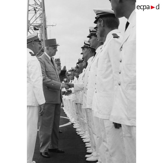 Le général Charles De Gaulle, président de la République, salue des officiers subalternes de marine aux côtés du capitaine de vaisseau Michel Teisserenc, commandant du croiseur De Grasse.