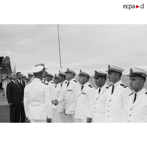 Le général Charles De Gaulle, président de la République, salue des officiers subalternes de marine aux côtés du capitaine de vaisseau Michel Teisserenc, commandant du croiseur De Grasse.