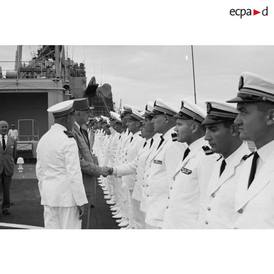 Le général Charles De Gaulle, président de la République, salue des officiers subalternes de marine aux côtés du capitaine de vaisseau Michel Teisserenc, commandant du croiseur De Grasse.