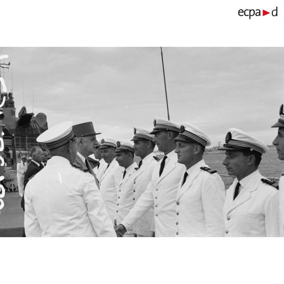 Le général Charles De Gaulle, président de la République, salue des officiers subalternes de marine aux côtés du capitaine de vaisseau Michel Teisserenc, commandant du croiseur De Grasse.