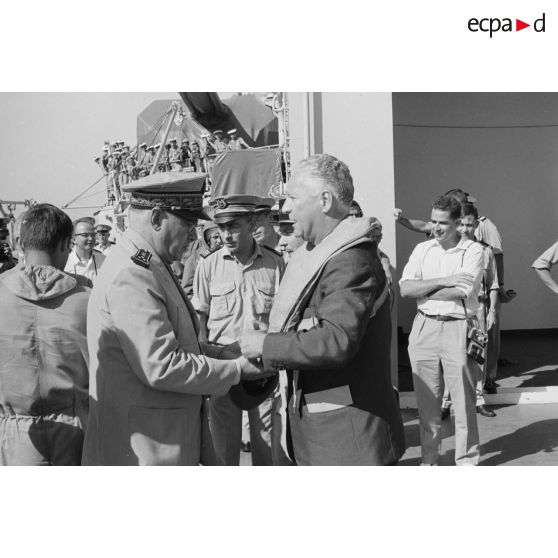 Pierre Messmer, ministre des Armées, est équipé d'un gilet de sauvetage pour son départ en hélicoptère, par le vice-amiral Jean Lorain, commandant du groupe opérationnel des expérimentations nucléaires (GOEN), à bord du croiseur De Grasse après le déclenchement de l'essai nucléaire Bételgeuse sur l'atoll de Moruroa.