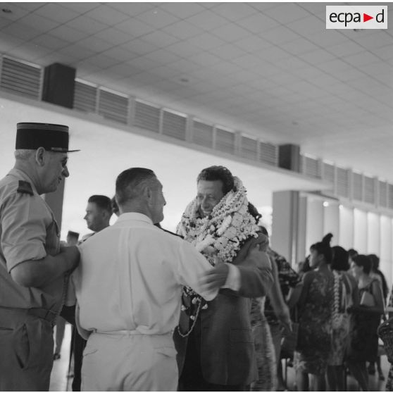 Départ à l'aéroport de Camussot (?), commandant l'aviso-escorteur Francis Garnier (F730), des colliers de fleurs autour du cou, salué par un commandant et un officier de marine.