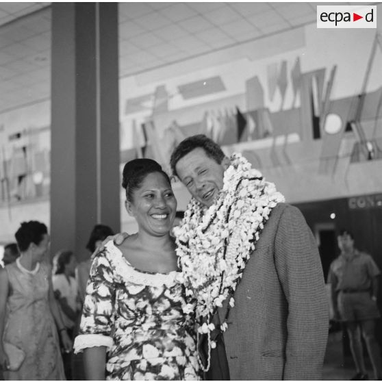 Départ à l'aéroport de Camussot (?), commandant l'aviso-escorteur Francis Garnier (F730), des colliers de fleurs autour du cou, salué par une femme polynésienne.