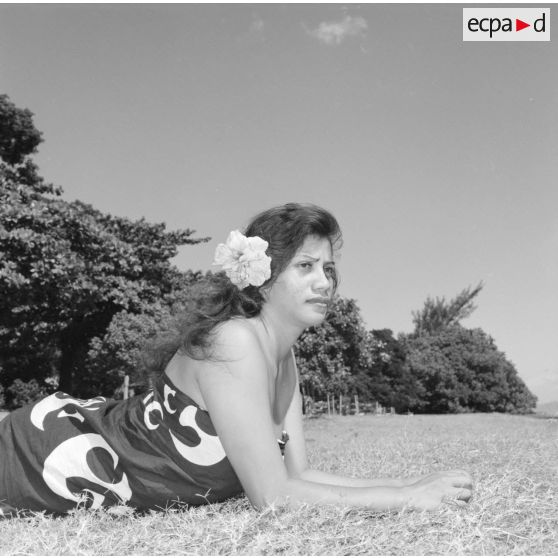 Fêtes du Juillet ou fête du Tiurai à Papeete en 1964. Portrait d'une jeune femme polynésienne au bord du rivage.