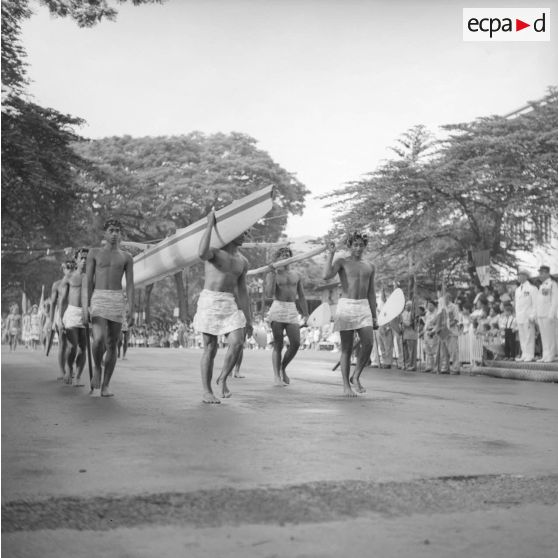 Fêtes du Juillet ou fête du Tiurai à Papeete en 1964. Défilé de pirogue portée par des piroguiers.