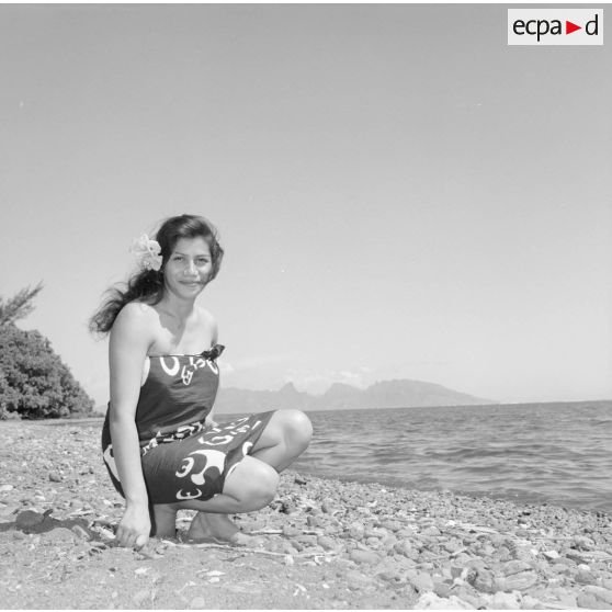 Fêtes du Juillet ou fête du Tiurai à Papeete en 1964. Portrait d'une jeune femme polynésienne au bord du rivage. En arrière-plan, l'île de Moorea.