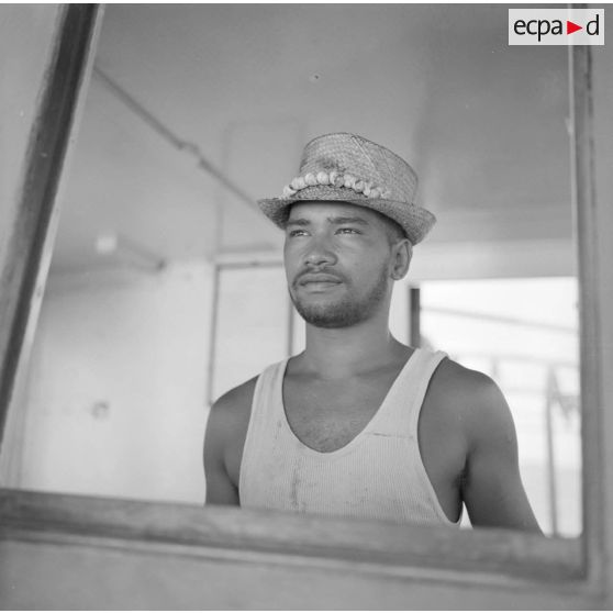 Portrait d'un jeune homme polynésien à bord d'un bateau sur le site de Moruroa en 1964 [cf également photo précédente T 6].