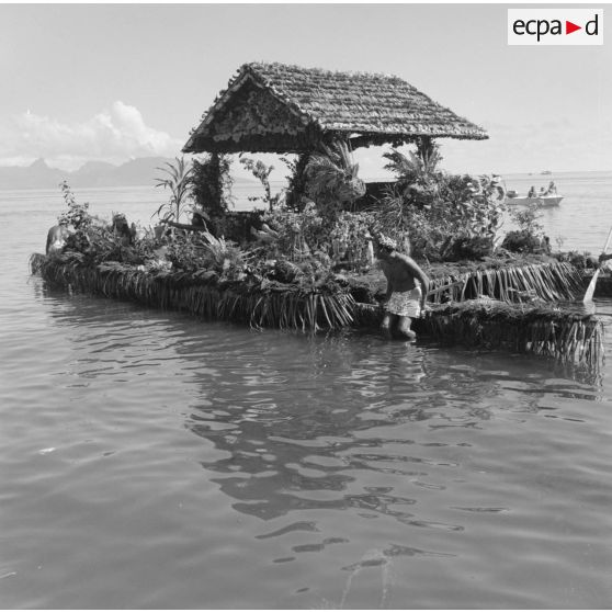 Fêtes de Juillet ou fête du Tiurai à Papeete en 1964. Pirogue fleurie. En arrière-plan, l'île de Moorea.