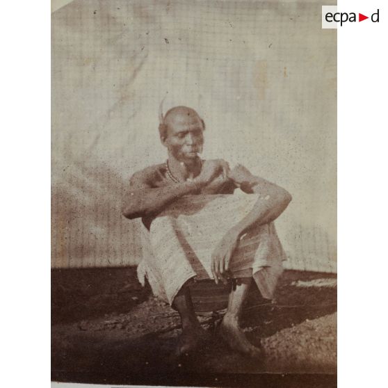 [Un homme fume assis par terre, s.d.]