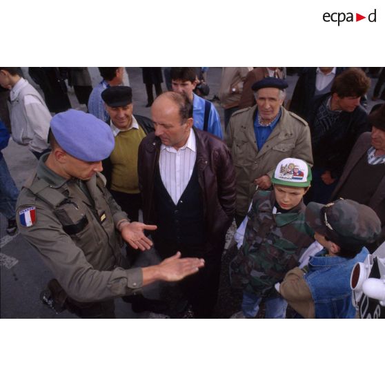 Lieutenant du 2e régiment d'infanterie de marine (2e RIMa) échangeant avec des hommes et des enfants de Karlovac à l'arrivée des troupes.